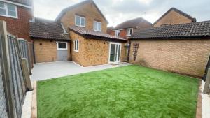 a backyard with a green lawn in front of some houses at Cosy 4 bedroom holiday let Stevenage 22mins from London on the train in Stevenage