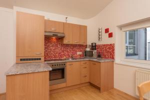 a kitchen with wooden cabinets and a brick wall at Appartements Maria Stewart by Schladming-Appartements in Schladming