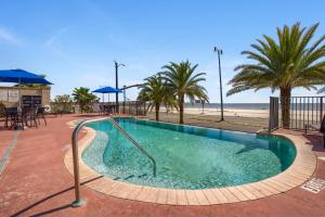 a swimming pool next to a beach with palm trees at Holiday Inn Express - Gulfport Beach by IHG in Gulfport