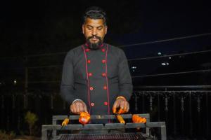 a man cooking hot dogs on a grill at SaffronStays The Perch in Kasauli