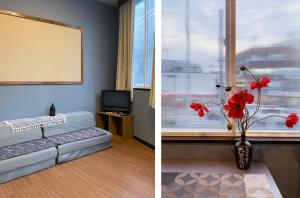 una camera con un letto e un vaso con fiori rossi di Tomi Home 2F a Tokyo