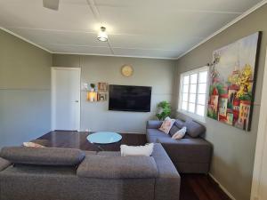 uma sala de estar com um sofá e uma mesa em Entire 3 bedroom house 2000 m2 - 5 mins WALK to Torquay Beach, Hervey Bay em Hervey Bay