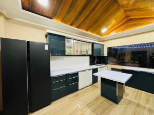 a kitchen with black cabinets and a wooden ceiling at Kadwali Villa with Private Pool in Ujjain