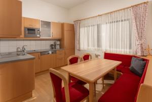 a kitchen and dining room with a wooden table and red chairs at Appartements Maria Stewart by Schladming-Appartements in Schladming