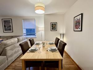 una sala da pranzo con tavolo e divano di La Scala Inverness City Apartment a Inverness