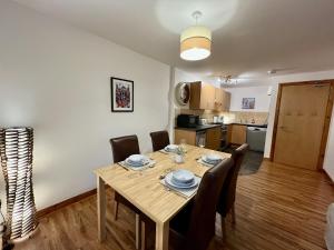 a dining room table with chairs and a kitchen at La Scala Inverness City Apartment in Inverness