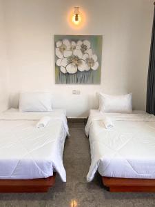 two beds sitting next to each other in a room at Flower Home ផ្ទះសំណាក់ ហូមផ្កា in Sihanoukville