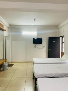 a hospital room with two beds and a tv at Regalia Wayanad in Kalpetta