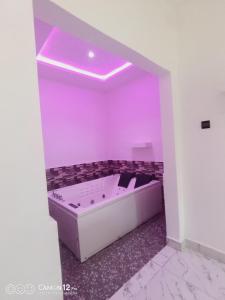 Habitación con baño púrpura con bañera. en DE LUXE, en Porto Novo