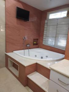 a bathroom with a tub with a tv on the wall at WHITEVILLA 5 ROOMS in Pune