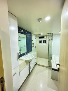 a white bathroom with a sink and a tub at WHITEVILLA 5 ROOMS in Pune