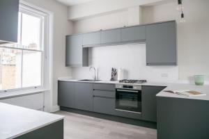 een keuken met grijze en witte kasten en een raam bij Spectacular flat located in prime Notting Hill in Londen