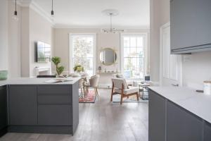 een keuken met witte werkbladen en een woonkamer bij Spectacular flat located in prime Notting Hill in Londen