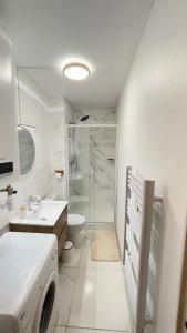 ein weißes Badezimmer mit einem Waschbecken und einer Waschmaschine in der Unterkunft Studio neuf cosy, Cinema Room, moderne avec Fibre, Gare RER C, JO Paris 2024 in Brétigny-sur-Orge