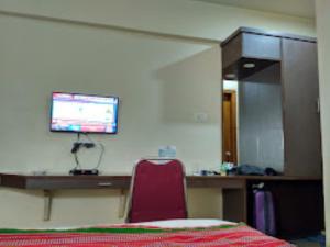 Habitación con escritorio y TV en la pared. en Hotel Yaiphabaa , Imphal, en Imphal