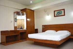 a bedroom with a large bed and a mirror at Hotel Yaiphabaa , Imphal in Imphal