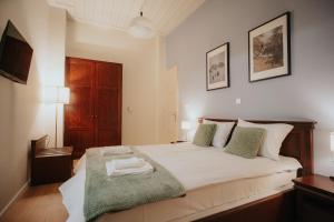 um quarto com uma grande cama branca com almofadas verdes em 1909 Guesthouse em Kalavrita