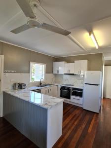 cocina grande con electrodomésticos blancos y suelo de madera en Entire 3 bedroom house 2000 m2 - 5 mins WALK to Torquay Beach, Hervey Bay en Hervey Bay