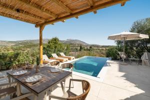 un patio con tavolo, sedie e piscina di Massari Hills Luxury Living a Malona Village