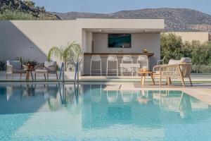 a swimming pool with chairs and a table next to a house at Filia Luxury Suites in Stalís