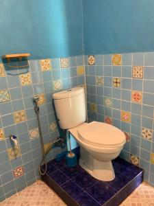 a bathroom with a toilet in a blue tiled room at Mario Lakeside Apartments in Tuk Tuk