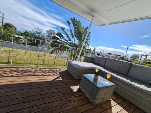 un patio avec un canapé et une table sur une terrasse dans l'établissement Entire 3 bedroom house 2000 m2 - 5 mins WALK to Torquay Beach, Hervey Bay, à Hervey Bay