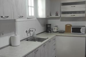 a white kitchen with a sink and a microwave at Kostas House in Kouspádes