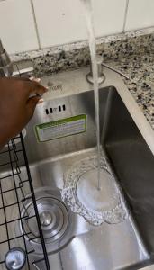 a person is pouring water into a sink at Regium Apartment in Lekki