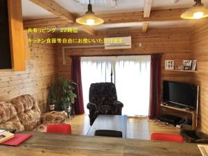 uma sala de estar com uma mesa e uma grande janela em 青森伝統芸能を楽しめる繭子の宿 em Hachinohe