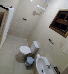 a white bathroom with a toilet and a sink at PANTAI POUSADA in Trindade