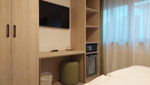 sypialnia z telewizorem, łóżkiem i szafką w obiekcie Hotel Nessi Locarno w mieście Locarno