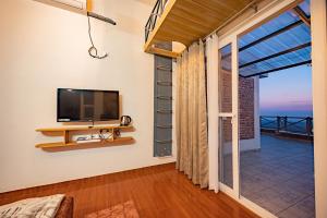 a living room with a tv and a large window at Secluded by The StayCationer in Kandogal