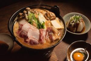 un tazón de sopa con carne y otros alimentos en una mesa en こもる五所川原 en Goshogawara