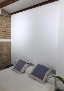 a white bedroom with a bed with two pillows at Estudio Pau @VALENCIAYOLE in Valencia