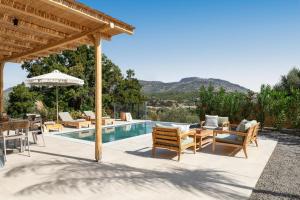 un patio con tavolo e sedie accanto alla piscina di Massari Hills Luxury Living a Malona Village