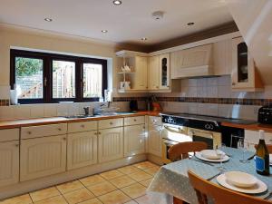 a kitchen with white cabinets and a table with chairs at Caer Dderwen Oak Field family home in Dolgellau in Dolgellau