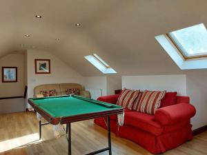 a living room with a red couch and a pool table at Caer Dderwen Oak Field family home in Dolgellau in Dolgellau