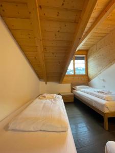 two beds in a room with a wooden ceiling at Appartamento Rio Duron in Campitello di Fassa