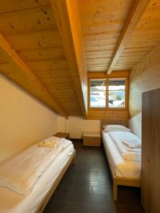 two beds in a room with wooden ceilings at Appartamento Rio Duron in Campitello di Fassa