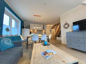 uma sala de estar com um sofá e uma mesa em Hafenperle 21 - Traum am Hafen em Norddeich