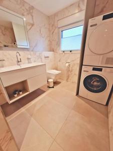 uma casa de banho com uma máquina de lavar roupa e um lavatório em Wilde Brise 2 Topniveau in Toplage mit Sauna em Norden
