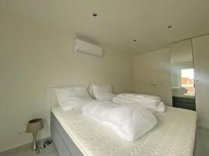 een wit bed met witte lakens en kussens bij Die Zimmerei 5 in Krummhörn