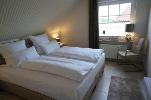 ノルトダイヒにあるKüstenblick 3のベッドルーム1室(白いシーツ付きのベッド1台、窓付)