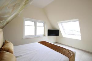 a white bedroom with a bed and two windows at Seeblick 3 in Norddeich