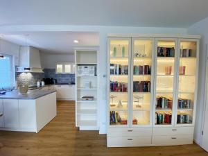 une cuisine avec une armoire blanche remplie de livres dans l'établissement Wilde Brise - Ihr Luxusbungalow in Norddeich, à Norddeich