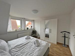 a bedroom with a white bed and a window at Deichblick 2 - Traumhaft am Deich in Norddeich