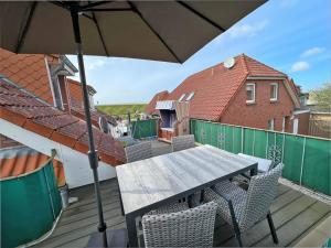 a table and chairs on a deck with an umbrella at Deichblick 2 - Traumhaft am Deich in Norddeich