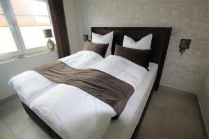 1 dormitorio con 1 cama grande con sábanas y almohadas blancas en Seeblick 6 - Traumferien am Hafen en Norddeich