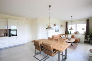 a kitchen and living room with a wooden table and chairs at Seeblick 5 - Luxus am Hafen in Norddeich