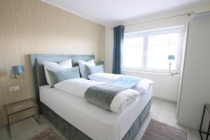 a bedroom with a bed with white sheets and a window at Seeblick 5 - Luxus am Hafen in Norddeich